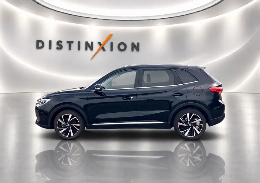 Vue de profil côté gauche du SUV MG ZS 1.5 hybrid noir, avec jantes alliage et toit panoramique en arrière-plan lumineux.