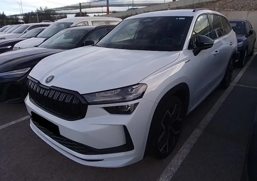 Vue 3/4 avant droite d’un Skoda Kodiaq blanc Glacier avec calandre noire et jantes anthracite 20 pouces.