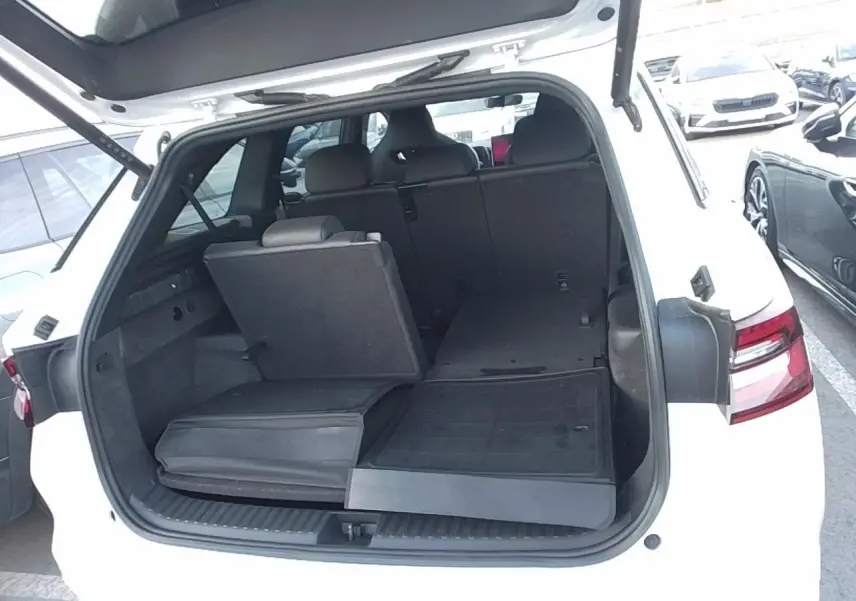 Vue arrière du Skoda Kodiaq blanc Glacier 2025 avec hayon ouvert et banquette arrière partiellement rabattue.