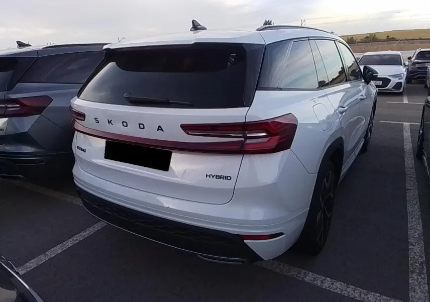 Vue 3/4 arrière droite d’un Skoda Kodiaq blanc Glacier hybride avec feux arrière LED et vitres surteintées.