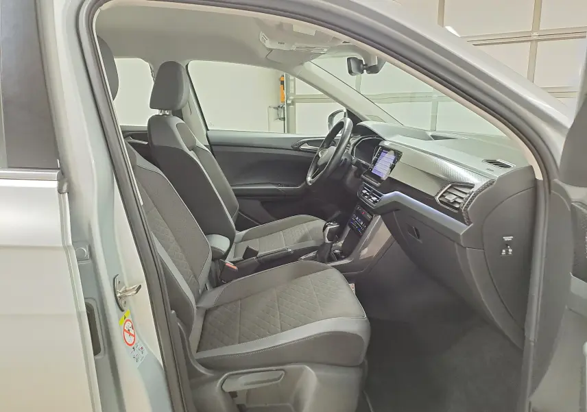 Vue intérieure côté conducteur du Volkswagen T-Cross 2022 argent, montrant sièges et tableau de bord moderne.