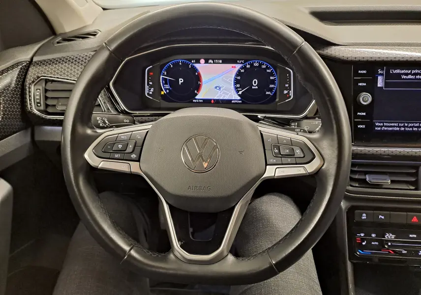 Vue intérieure centrée sur le volant noir du Volkswagen T-Cross 2022 avec tableau de bord numérique et écran tactile.