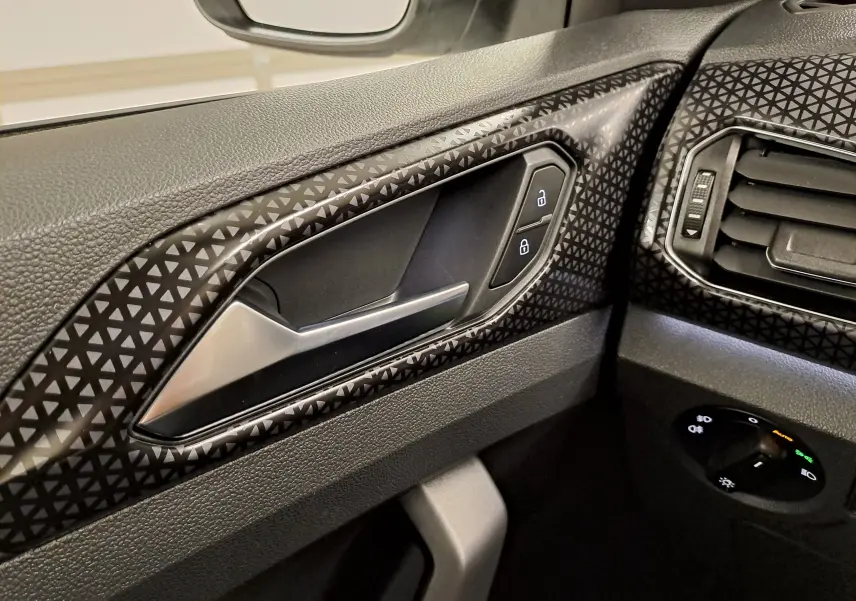 Détail intérieur côté gauche du Volkswagen T-Cross 2022, montrant la poignée de porte et les commandes de verrouillage.