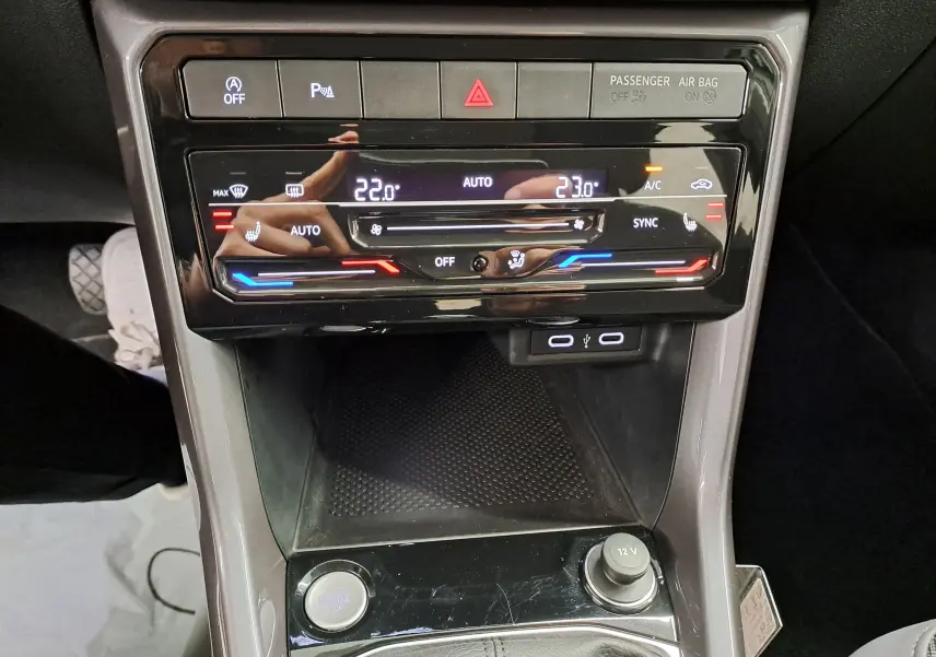 Vue rapprochée du tableau de bord central du Volkswagen T-Cross 2022, avec commandes climatisation digitale et ports USB visibles.