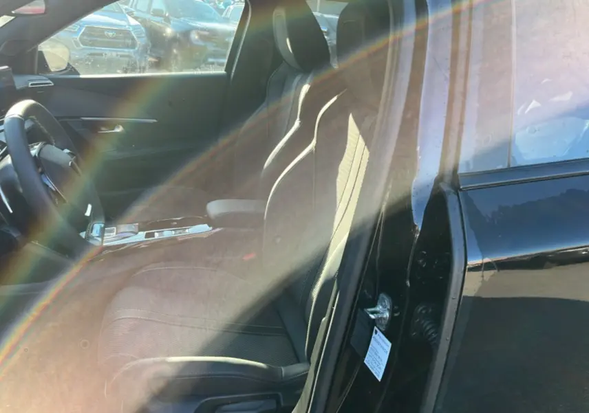 Vue intérieure côté conducteur du Peugeot 2008 noir perla nera, mettant en valeur les sièges et le volant cuir multifonctions.