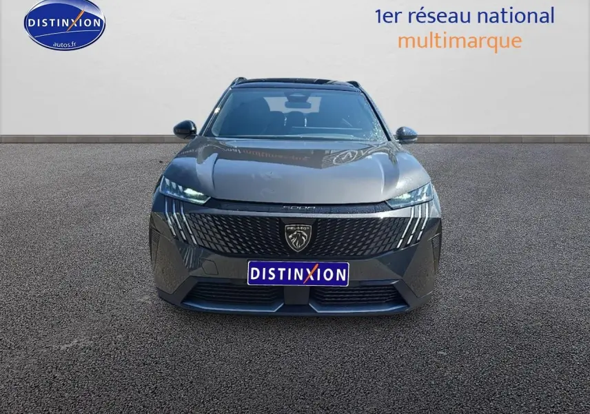 Vue de face du Peugeot 5008 Hybrid 145 GT gris titane avec calandre noire et phares LED allumés.
