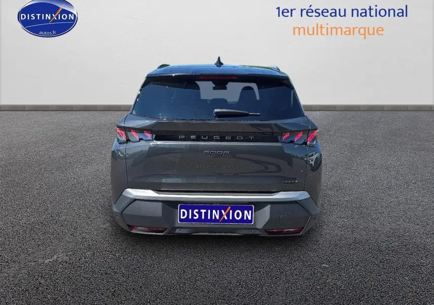 Vue arrière d’un Peugeot 5008 Hybrid gris titane avec feux LED caractéristiques et hayon électrique fermé.