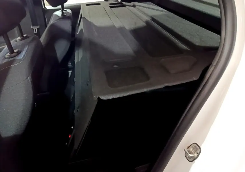 Vue intérieure arrière droite du coffre ouvert d'une Peugeot 208 blanche, montrant la banquette arrière rabattue et l'espace de chargement.