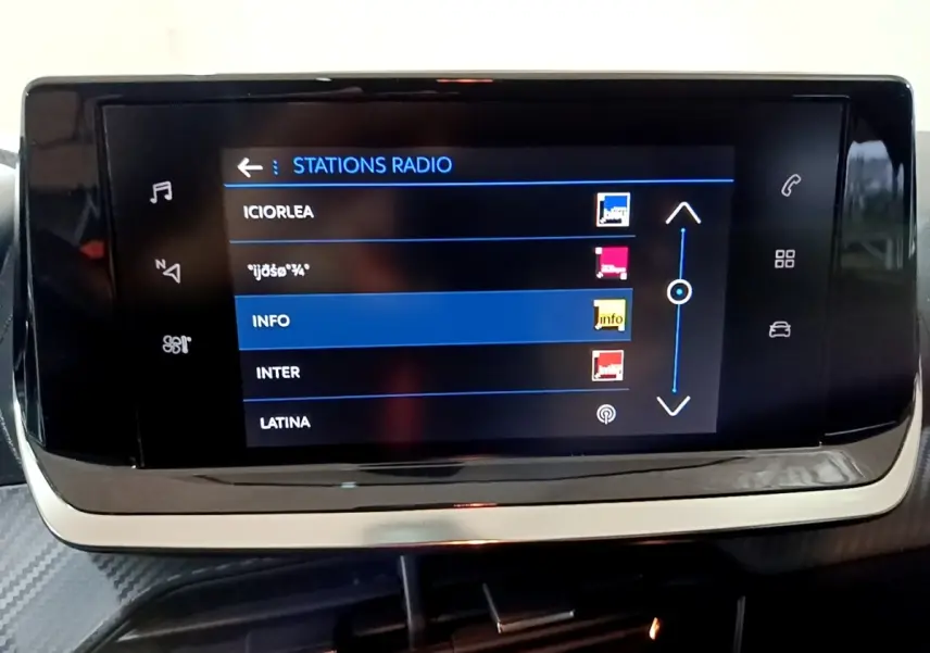 Écran tactile central affichant les stations radio dans l’habitacle d’une Peugeot 208 blanche, vue de face.