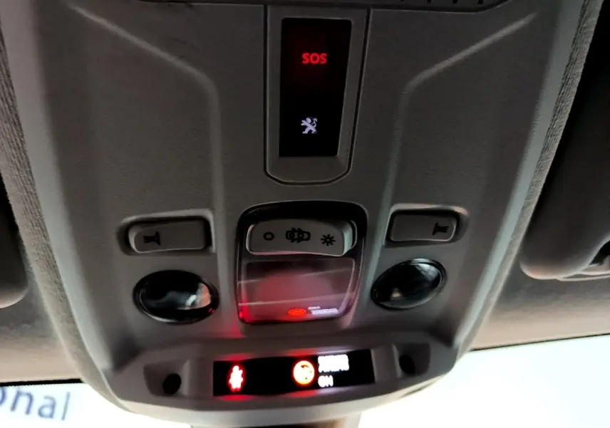 Vue intérieure en gros plan du plafonnier gris avec bouton SOS et éclairage dans une Peugeot 208 blanche.