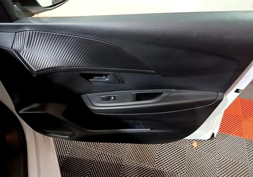 Vue intérieure côté gauche de la porte avant blanche du Peugeot 208 1.5 BlueHDi avec insert noir texturé.