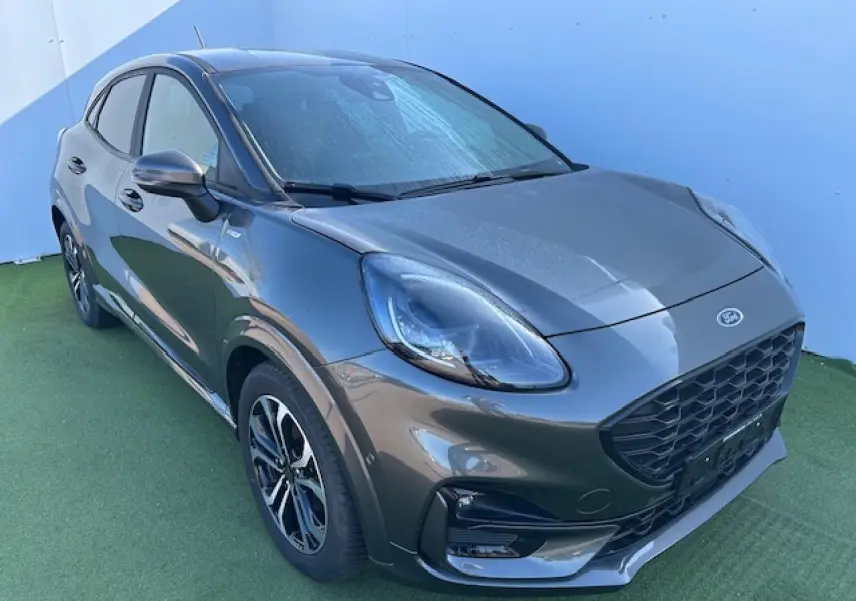 Vue 3/4 avant droit d'un Ford Puma gris magnetic avec calandre noire et jantes alliage 17 pouces.