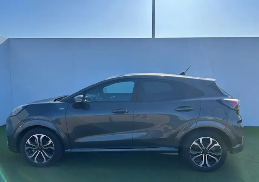 Vue de profil côté gauche d'un Ford Puma gris Magnetic avec jantes alliage 17 pouces et toit blanc.