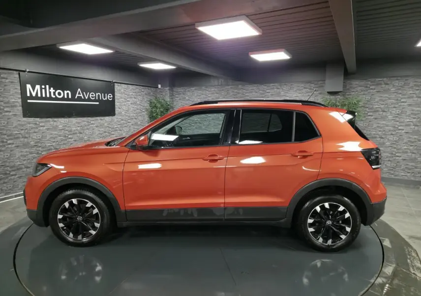 Volkswagen T-Cross orange Energy vue de profil côté gauche, jantes alliage noires et toit noir contrasté.
