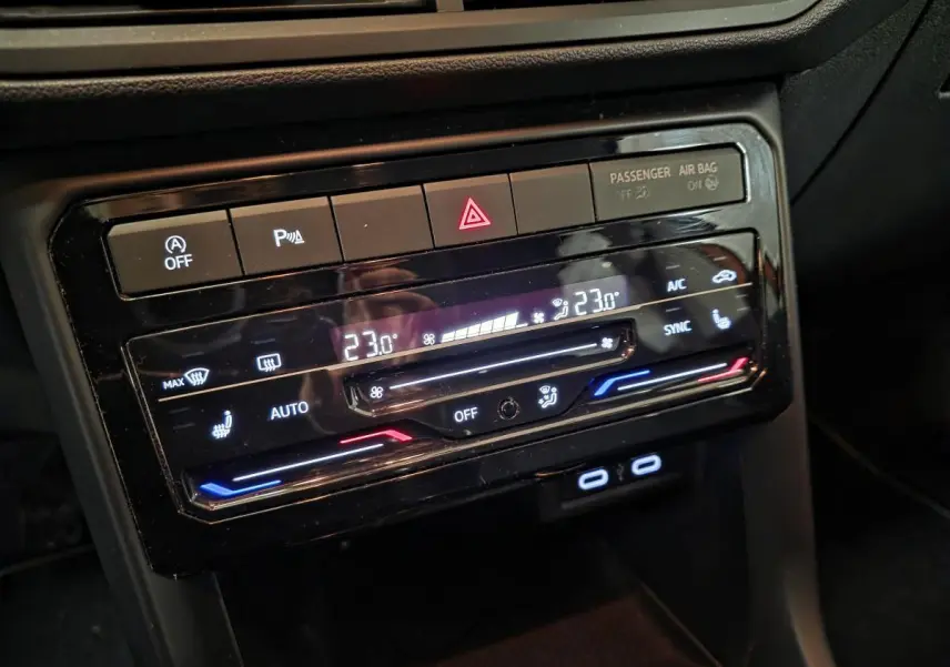 Gros plan sur la console centrale noire du Volkswagen T-Cross 1.0 TSI Active avec commandes de climatisation digitales.