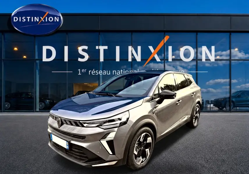 Renault Symbioz gris cassiope en 3/4 avant droit, avec jantes alu et calandre moderne devant showroom Distinxion.