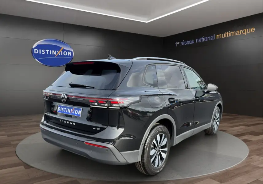 Vue 3/4 arrière droite du Volkswagen Tiguan noir avec feux arrière LED et jantes alliage en showroom.