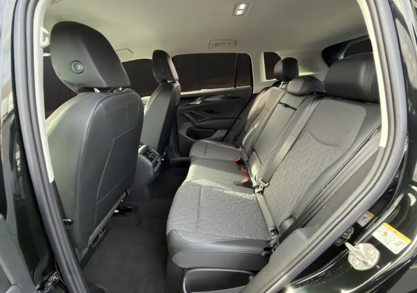Vue intérieure arrière côté droit du Volkswagen Tiguan noir 2026, sièges tissu et cuir gris avec accoudoirs centraux.
