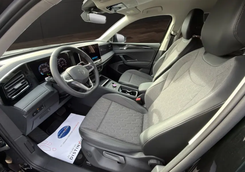 Vue intérieure côté conducteur du Volkswagen Tiguan 2026 noir, montrant sièges tissu gris et tableau de bord digital.