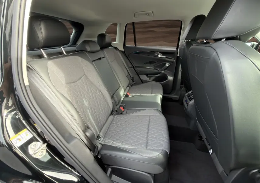 Vue intérieure arrière côté gauche du Volkswagen Tiguan 2026 noir, montrant la banquette tissu et cuir gris avec accoudoir central.