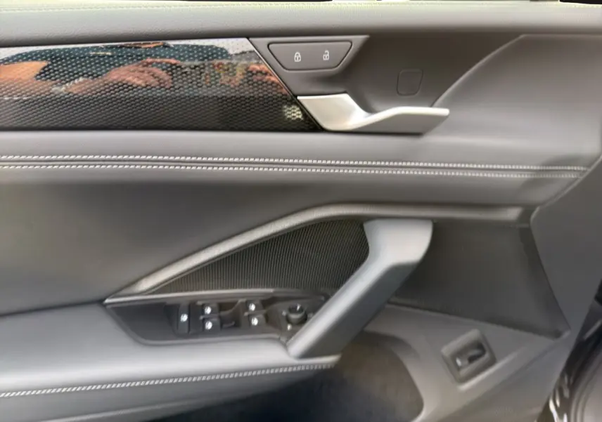 Détail de la porte intérieure côté conducteur du Volkswagen Tiguan noir, avec commandes électriques et finition cuir noire.