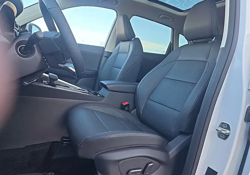 Vue intérieure côté conducteur du MG ZS blanc 2026, sièges en similicuir noir avec toit panoramique en verre visible.