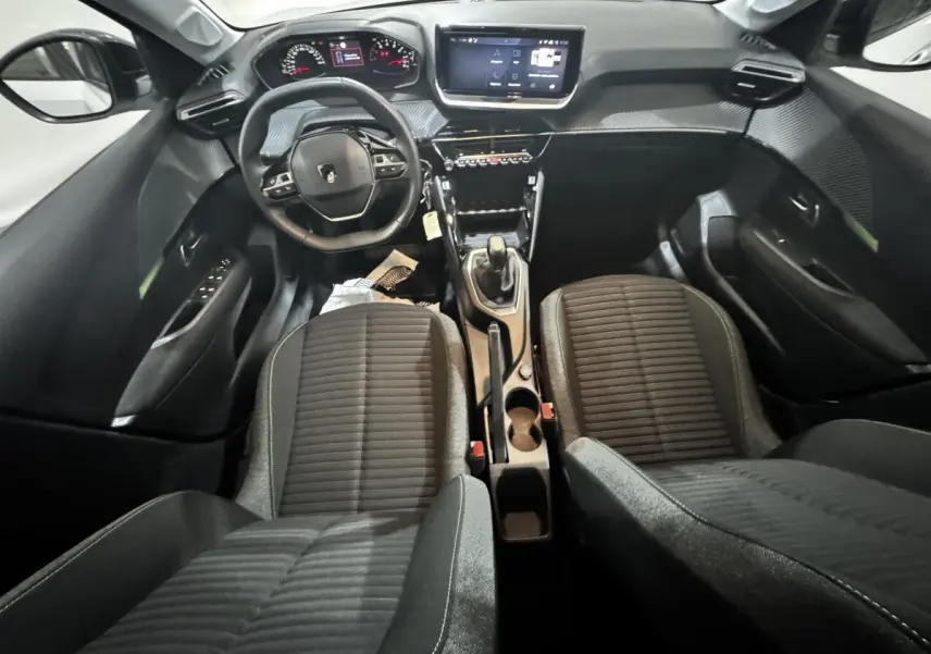 Vue intérieure avant de la Peugeot 208 PureTech 75 S&S Active 2024, sièges noirs et tableau de bord avec écran tactile central.