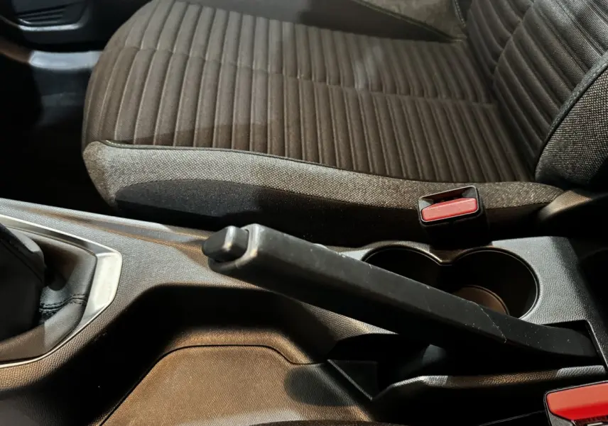 Gros plan sur la console centrale et le frein à main de la Peugeot 208 PureTech 75 S&S Active avec siège tissu marron.