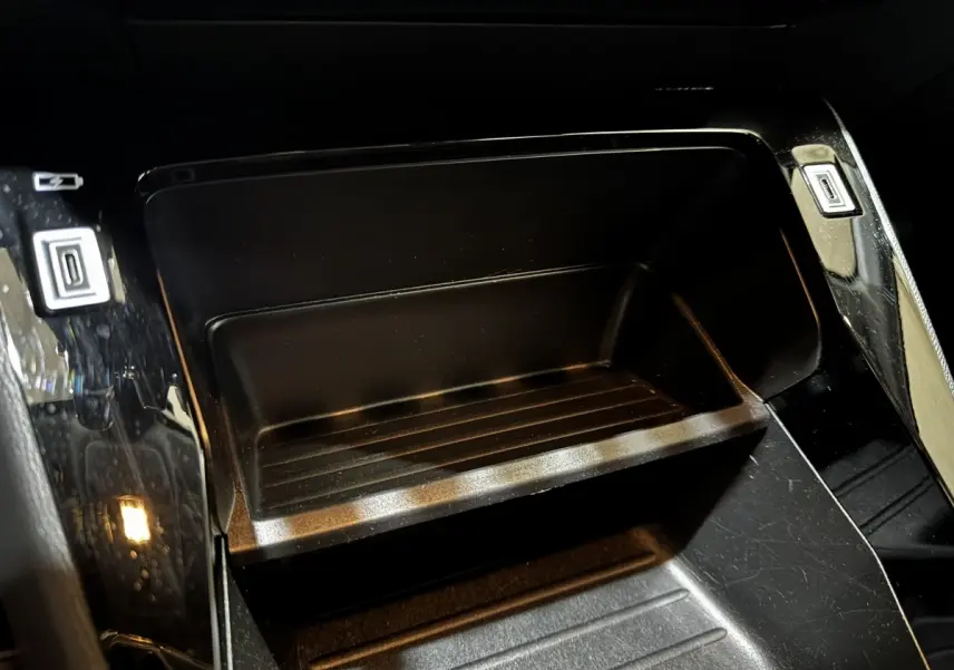 Gros plan intérieur sur le rangement central noir brillant de la Peugeot 208 PureTech 75 S&S Active 2024.