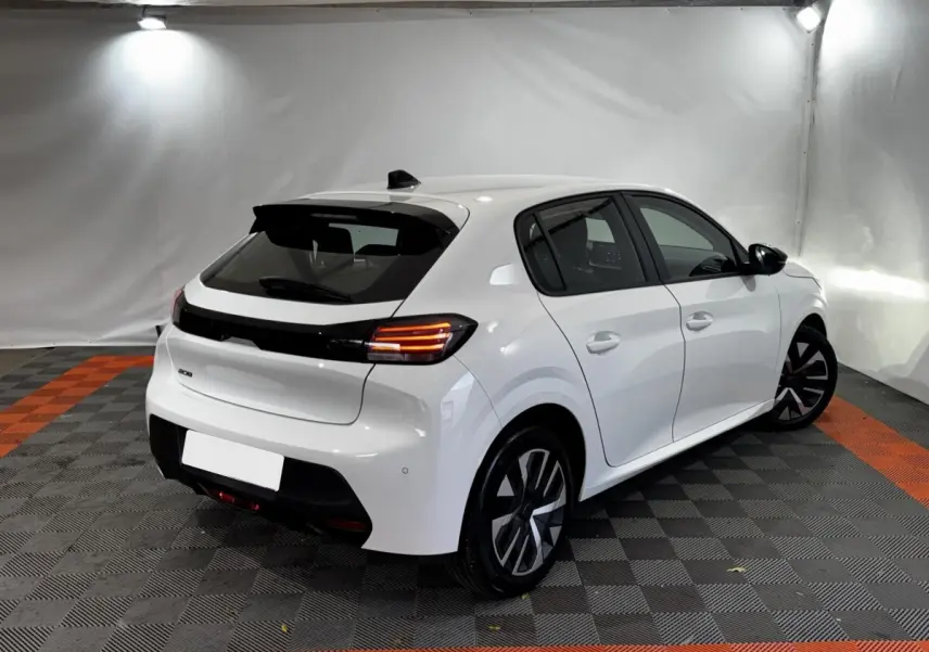 Peugeot 208 PureTech blanc vue 3/4 arrière droit dans un studio avec feux arrière LED allumés.