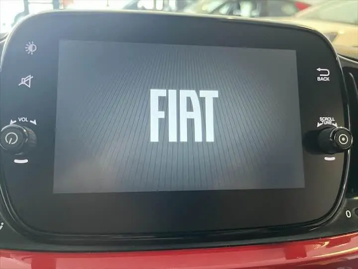 Écran tactile central affichant le logo FIAT, avec une partie de la planche de bord rouge visible en bas.