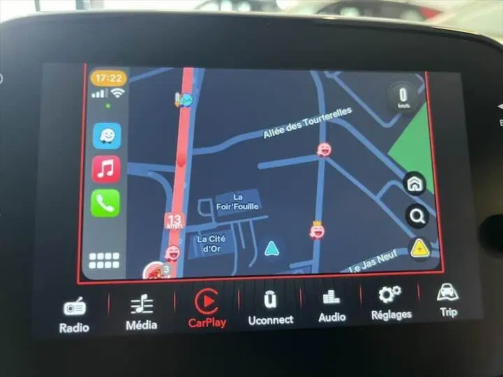 Écran tactile du système multimédia FIAT 500 2023 affichant la navigation CarPlay avec carte et icônes colorées.