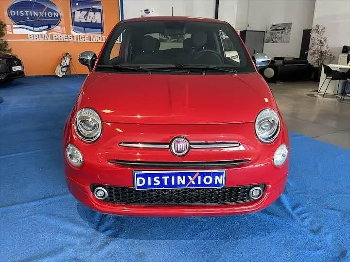 Vue avant d'une FIAT 500 rouge brillante en showroom avec logo Distinxion sur la plaque avant.