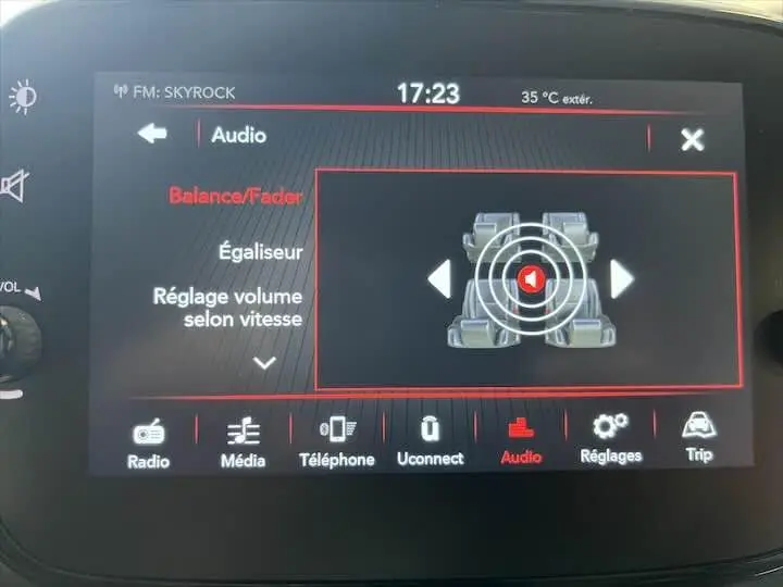 Écran tactile du système audio de la Fiat 500 hybride rouge, affichant les réglages de balance et fader.