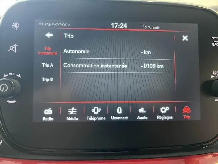 Écran tactile central de la Fiat 500 rouge 2023 affichant les données de consommation et autonomie en intérieur.