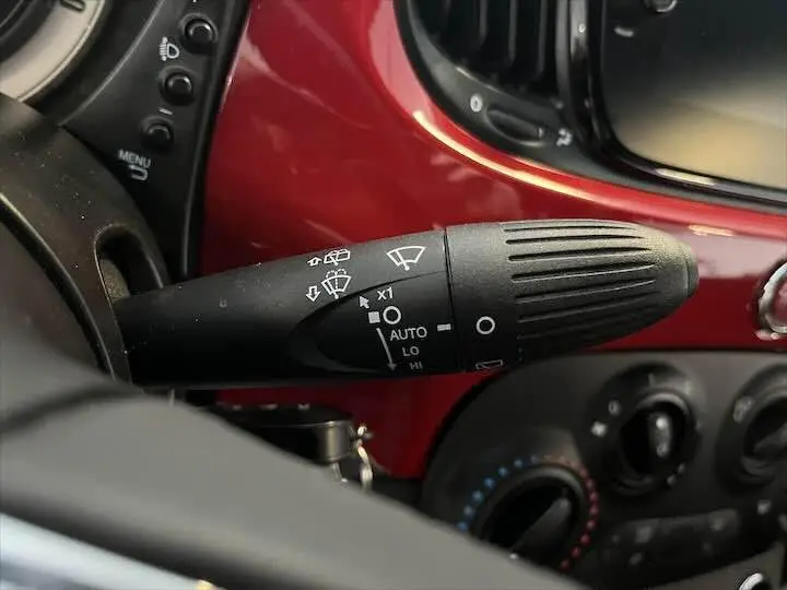 Gros plan sur la commande d’essuie-glace dans l’habitacle rouge brillant d’une Fiat 500 hybride 2023.