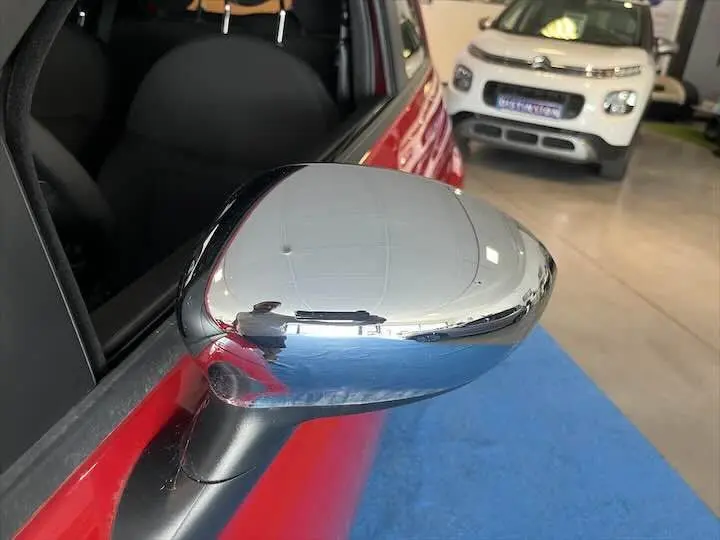Rétroviseur chromé côté gauche d'une FIAT 500 rouge vue en gros plan dans un showroom.