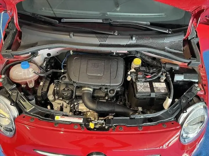 Vue plongeante sur le moteur d'une FIAT 500 rouge 2023, avec capot ouvert et détails du compartiment moteur visibles.