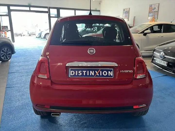 Vue arrière d'une FIAT 500 rouge hybride exposée en showroom avec plaque Distinxion bien visible.