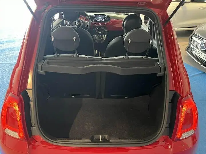 Coffre ouvert vu de l'arrière d'une FIAT 500 rouge 2023, intérieur noir avec tableau de bord visible.