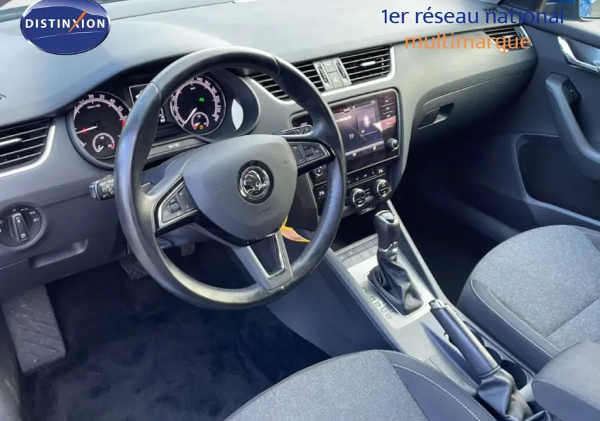 Vue intérieure côté conducteur de la Skoda Octavia Combi 2019, tableau de bord et volant en cuir avec console centrale et boîte auto.