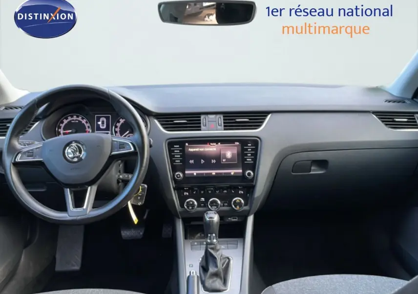 Vue frontale de l’intérieur d’une Skoda Octavia Combi 2019, tableau de bord et volant noir avec écran central tactile.