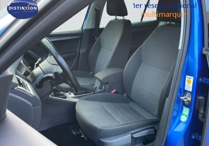 Vue intérieure côté conducteur de la Skoda Octavia Combi bleu racing, sièges tissu gris et volant noir visible.