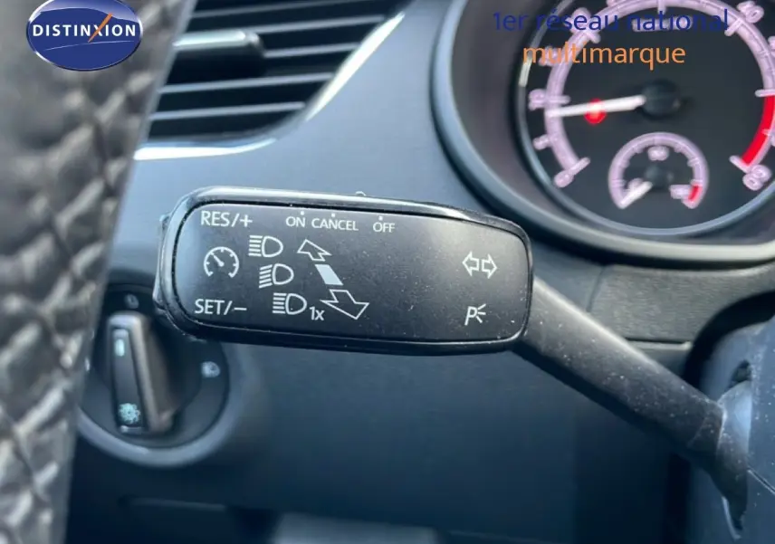 Gros plan sur la commande de régulateur de vitesse à gauche du volant dans l’habitacle d’une Skoda Octavia Combi bleu racing metal.