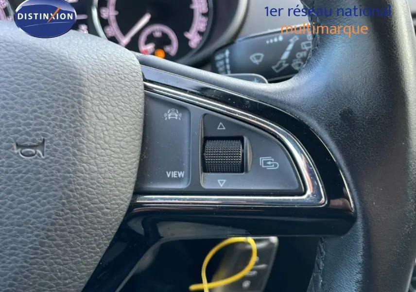 Gros plan sur le volant noir de la Skoda Octavia Combi 2019, montrant les commandes multifonctions et le tableau de bord flou.