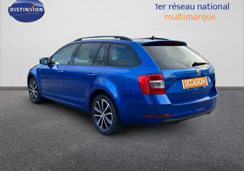 Vue 3/4 arrière gauche d’une Skoda Octavia Combi bleu racing metal avec jantes alliage et toit ouvrant.