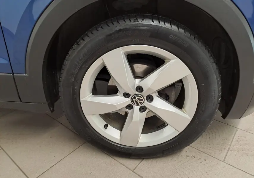Gros plan sur la roue avant gauche du Volkswagen T-Cross Bleu Récif, jante alliage à cinq branches.