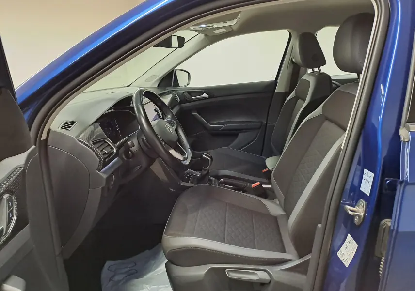 Vue intérieure côté conducteur du Volkswagen T-Cross Bleu Récif 2022, montrant sièges et tableau de bord moderne.