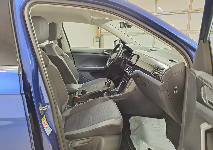 Vue intérieure côté gauche du Volkswagen T-Cross Bleu Récif 2022, montrant les sièges avant et le tableau de bord moderne.