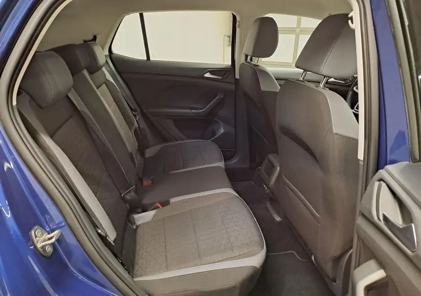 Vue intérieure arrière côté gauche du Volkswagen T-Cross bleu Récif 2022, montrant les sièges arrière en tissu noir avec surpiqûres.